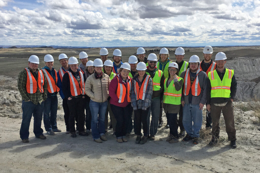 a group of people with hardhats and safety vests standing against a barren landscape